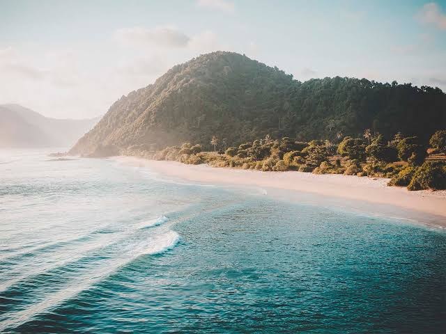 Plage sauvage et colline verdoyante dans le Sud de Lombok
